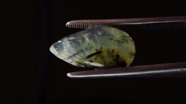 Arka plandaki cımbızda doğal yeşil taş var.