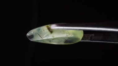 Arka plandaki cımbızda doğal yeşil taş var.