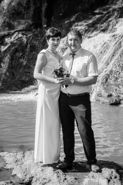 花嫁と新郎は滝の背景に立っています — ストック写真