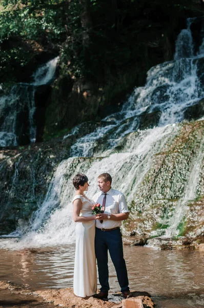 Das Brautpaar Steht Vor Dem Hintergrund Eines Wasserfalls — Stockfoto