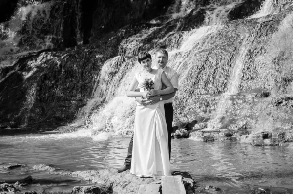 Bruden Och Brudgummen Står Mot Bakgrunden Ett Vattenfall — Stockfoto