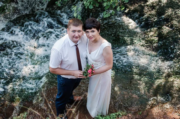 Das Brautpaar Steht Vor Dem Hintergrund Eines Wasserfalls — Stockfoto