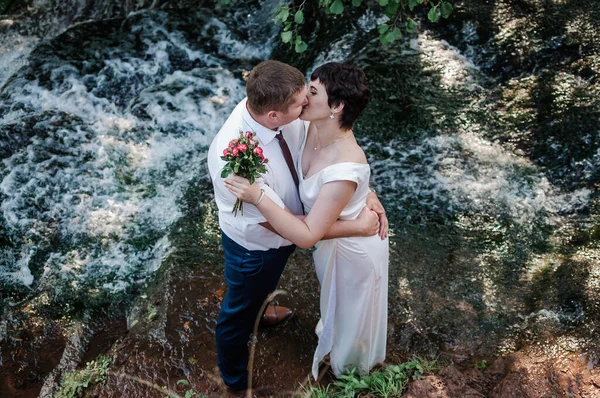 Bruden Och Brudgummen Står Mot Bakgrunden Ett Vattenfall — Stockfoto