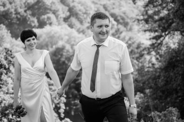 Yeni evliler ormanın arka planında el ele tutuşuyorlar. Bir kadının elini tutan bir erkek.