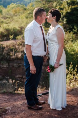 Yeni evliler ormanın arka planında el ele tutuşuyorlar. Bir kadının elini tutan bir erkek.