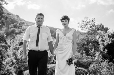 Yeni evliler ormanın arka planında el ele tutuşuyorlar. Bir kadının elini tutan bir erkek.