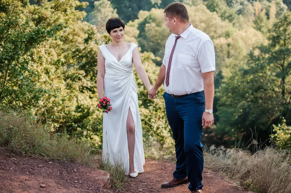 Frischvermählte Halten Händchen Auf Dem Hintergrund Des Waldes Ein Mann — Stockfoto