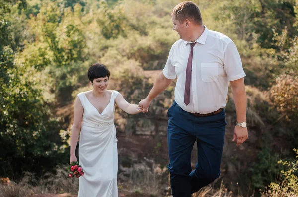 Frischvermählte Halten Händchen Auf Dem Hintergrund Des Waldes Ein Mann — Stockfoto