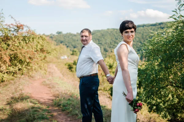 Frischvermählte Halten Händchen Auf Dem Hintergrund Des Waldes Ein Mann — Stockfoto