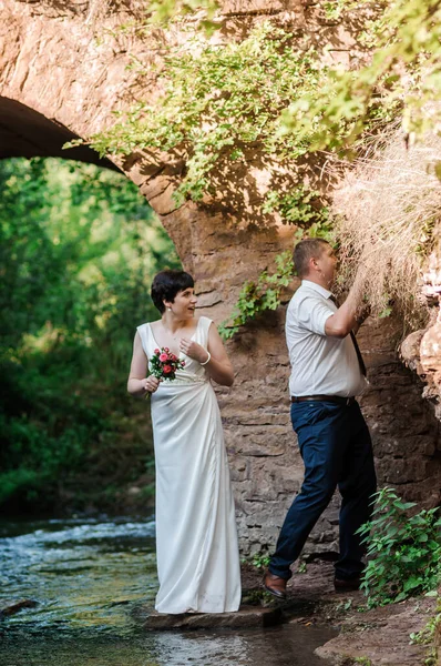 Recém Casados Abraçar Beijar Contra Fundo Água Arco Pedra — Fotografia de Stock