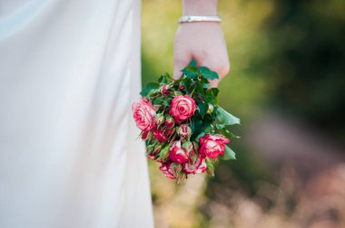 Ellerinde pembe güller olan bir buket