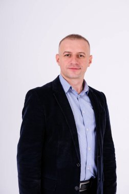 Mavi gömlekli, siyah pantolonlu ve beyaz arka planda mavi ceketli bir adam.