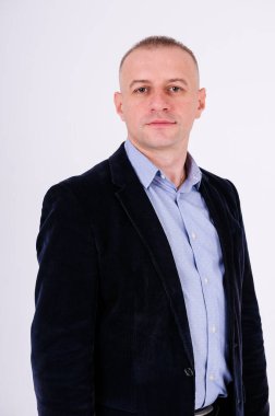 Mavi gömlekli, siyah pantolonlu ve beyaz arka planda mavi ceketli bir adam.