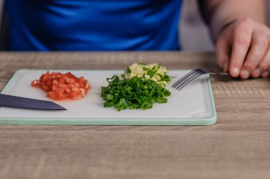 A man cuts green onions on a board