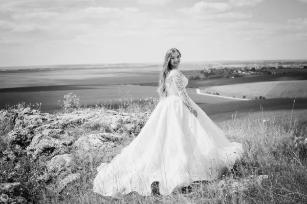 Dívka v bílých svatebních šatech stojí na pozadí krásné krajiny — Stock fotografie