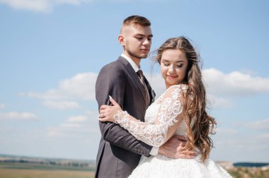 Kayaların arkasında sarılan yeni evliler.