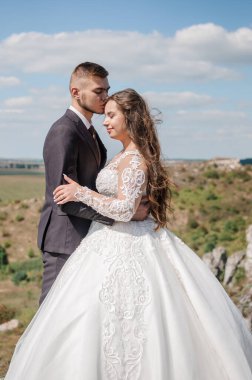 Kayaların arkasında sarılan yeni evliler.