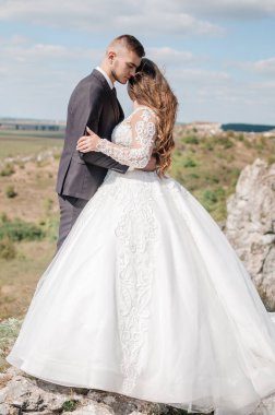 Kayaların arkasında sarılan yeni evliler.