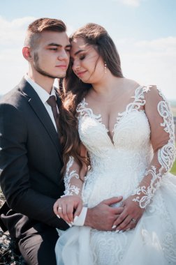 Yeni evliler kayaların ve güzel manzaranın arka planında sarılırlar.