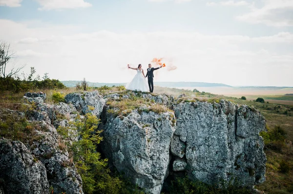 Frischvermählte Auf Dem Hintergrund Von Felsen Und Halten Bunten Rauch — Stockfoto