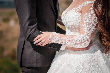 Yeni evliler güzel bir manzaranın arka planında sarılırlar.