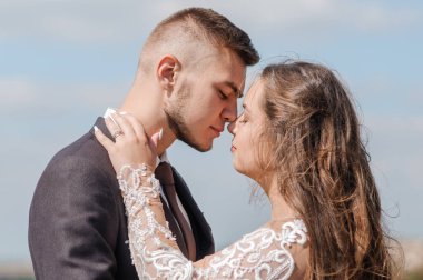 Yeni evliler güzel bir manzaranın arka planında sarılırlar.