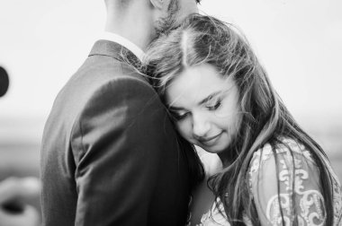 Yeni evliler güzel bir manzaranın arka planında sarılırlar.