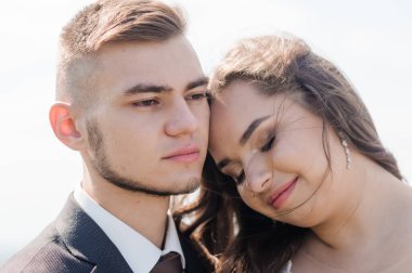 Yeni evliler güzel bir manzaranın arka planında sarılırlar.