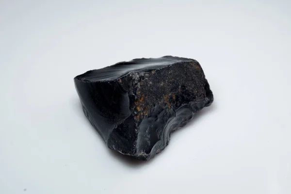 Pedra obsidiana preta natural sobre fundo branco — Fotografia de Stock