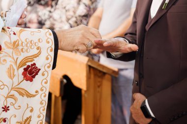 Bir rahip geleneksel Ortodoks Hıristiyan evlilik töreni sırasında nikah yüzüklerini törenle kutsayarak cübbe ve şapelin iç kısımlarına odaklanır.