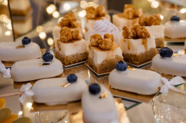 Cazip bir yakın çekim sergisi karamel soslu ve yaban mersiniyle süslenmiş zarif beyaz çikolatalı peynirli kekler. Tatlılar için mükemmel.