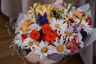 Güzelce düzenlenmiş bir bukette ayçiçekleri, papatyalar, güller, leylaklar ve bebek nefesi karışımı hediyeler, kutlamalar veya iç mekanlara renk katmak için ideal özellikler yer alıyor.