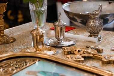 Yağ lambası, sürahi, haç ve bez de dahil olmak üzere altın sarısı renkleri vurgulayan sunaktaki kutsal gümüş vaftiz damarlarının ayrıntılı yaşamı