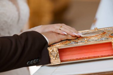 Geleneksel bir Ortodoks töreni sırasında gelin ve damadın eline odaklanan bir alyans takasını yakına çeker.