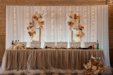 Çok şık bir düğün masasında parıldayan ışıklarla aydınlatılmış, altın çerçeveli otlarla vurgulanmış saf beyaz bir zemin ve akıcı bir masa koşucusu etkinlik planlama ve romantik kutlamalar için ideal.