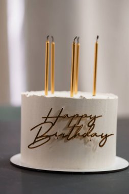 Narin el yazısıyla yazılmış beyaz pasta ve altın mumlar kutlama havası yaratıyor. Parti temaları ve etkinlik planlamaları için mükemmel.