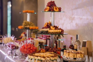 Taze meyve, hamur işi ve içeceklerle dolu katmanlı bir büfe, düğünler, partiler ya da sıcak ışıklandırmalı ve zarif sunumlu lüks toplantılar için mükemmel.