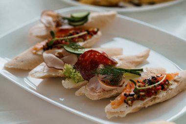 Füme somon, salatalık dilimleri, taze dereotu, salam ve kremalı sosla kaplı çok güzel hazırlanmış bir tabak bruschetta.