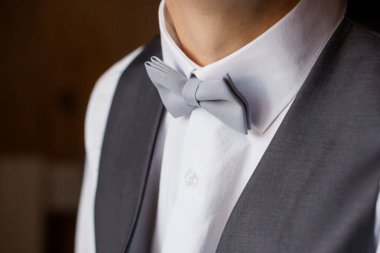 Pürüzsüz beyaz bir gömlek, gri papyon ve uyumlu bir yelek giyen, düğünler, galalar ve sofistike estetik etkinlikler için uygun rafine edilmiş resmi kıyafet giyen bir adamın yakın çekimi.