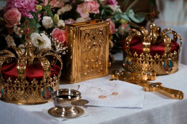 Kutsal Ortodoks Hıristiyan düğün töreni, altın taçlarla, dini kitaplarla, yüzüklerle ve çiçeklerle beyaz bir masa örtüsü üzerinde sıcak, saygıdeğer bir ambiyansla kurulur.