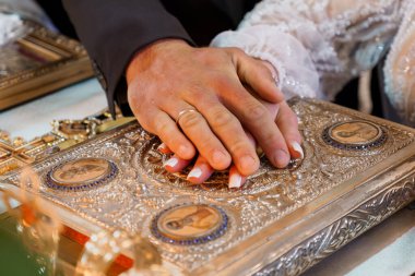 Bir gelin ve damadın özenle hazırlanmış altın bir ikon kitabı teslim edişini gösteren kutsal bir düğün anı. Kabartmalı tasarımlar ve kutsal semboller. İnancı ve birlikteliği simgeliyor.