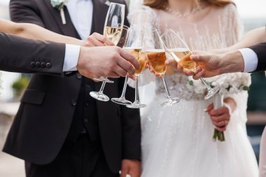 Gelin ve damadın romantik bir ortamda şampanya kadehleri kaldırdığı, kutlama ve birlik yakaladığı neşeli bir düğün sahnesi.