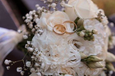 Hassas güller ve bebek nefesi üzerinde duran altın yüzüklerin yer aldığı romantik bir düğün buketi. Yumuşak doğal aydınlatma ve rüya gibi bir estetik ile aşk ve evliliği simgeliyor.