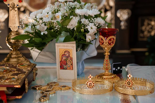 Altın bir kadeh, beyaz çiçek aranjmanı, dini bir simge ve süslü haçlar içeren huzurlu bir kilise sunağı, kutsal bir ortamda saygı ve ruhani ciddiyeti çağrıştırıyor.