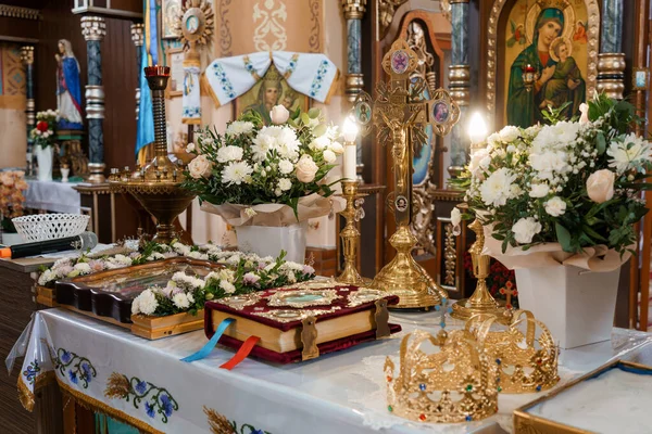 Altından haçlar, beyaz çiçek aranjmanları, dini simgeler ve sıcak ortam aydınlatması altında seremoni kitaplarının yer aldığı zengin bir Ortodoks kilisesi sunağı.