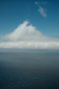 Mavi gökyüzünün altındaki geniş okyanus ve bulutlar, metin için kopyalama alanı olan dikey görüntü. Yüksek kalite fotoğraf