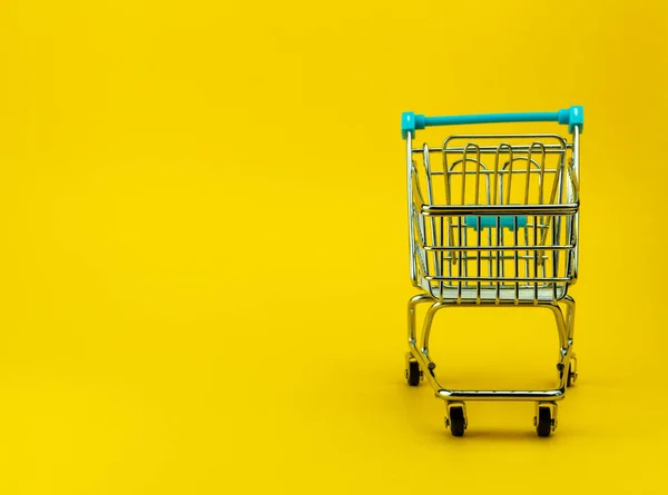 Carrito de compras vacío en fondo amarillo con copyspace. tienda minorista — Foto de Stock