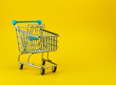 Boş alışveriş arabası, sarı arka planda izole edilmiş ve kopyalanmış. Perakende mağazası kavramı