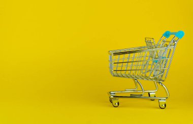 Sarı arka planda boş bir alışveriş arabasının yan görüntüsü. perakende mağazası