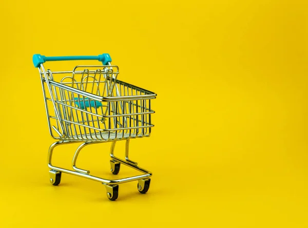 Carro de compras vacío aislado sobre fondo amarillo con copyspace. Concepto tienda minorista — Foto de Stock